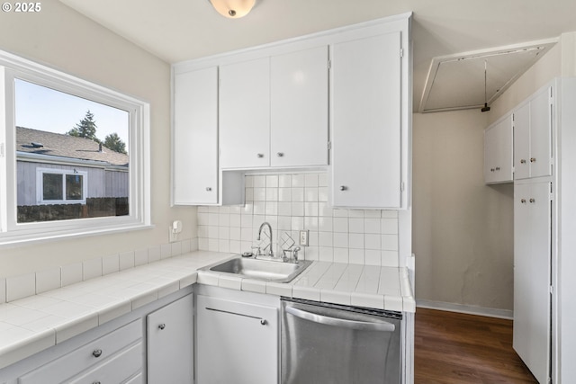 kitchen featuring white cabinetry, stainless steel dishwasher, tile counters, and sink