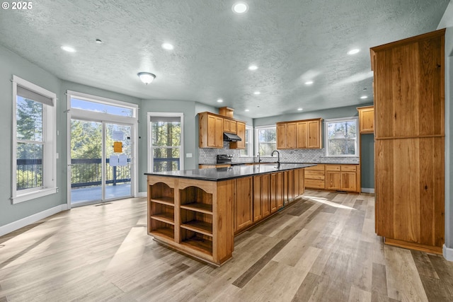 kitchen featuring backsplash, light hardwood / wood-style floors, a center island, and a textured ceiling