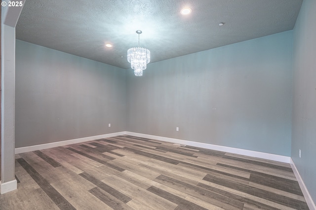 spare room featuring hardwood / wood-style flooring, a notable chandelier, and a textured ceiling