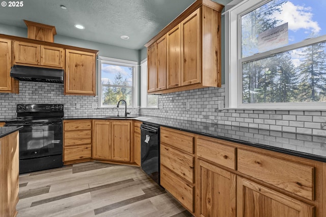 kitchen with ventilation hood, sink, dark stone counters, and black appliances