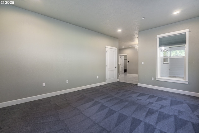 empty room with a textured ceiling and dark carpet