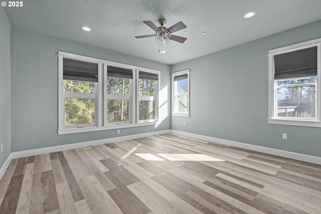 unfurnished room featuring a textured ceiling, light hardwood / wood-style flooring, and ceiling fan