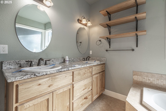 bathroom featuring tile patterned flooring, vanity, and tiled bath