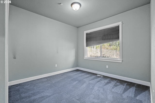 carpeted empty room featuring a textured ceiling