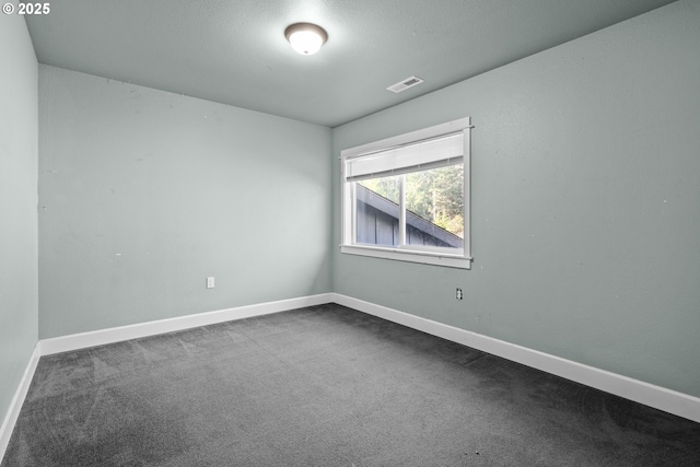 carpeted empty room featuring a textured ceiling