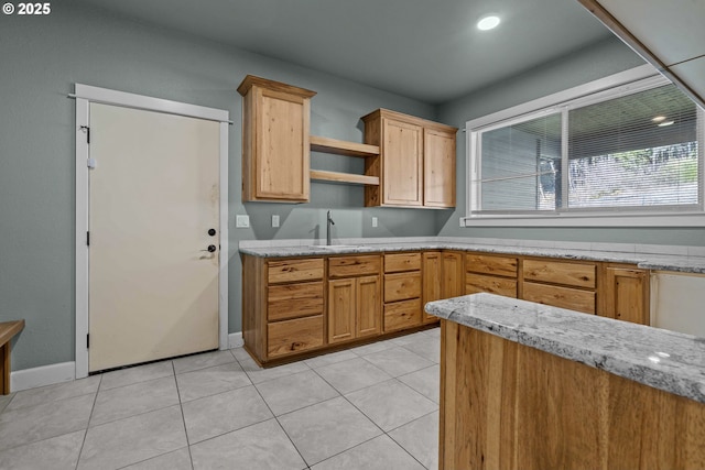 kitchen with light stone countertops, sink, and light tile patterned floors