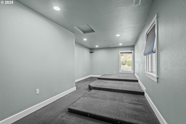 empty room with a textured ceiling and dark colored carpet
