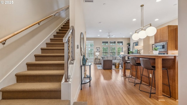 staircase featuring recessed lighting, a ceiling fan, wood finished floors, and visible vents