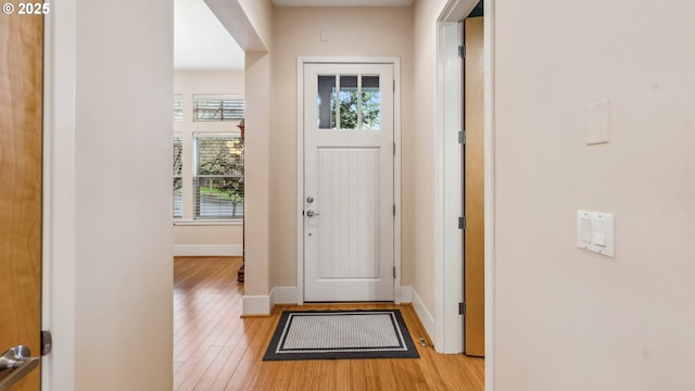 doorway to outside with baseboards and light wood-style flooring
