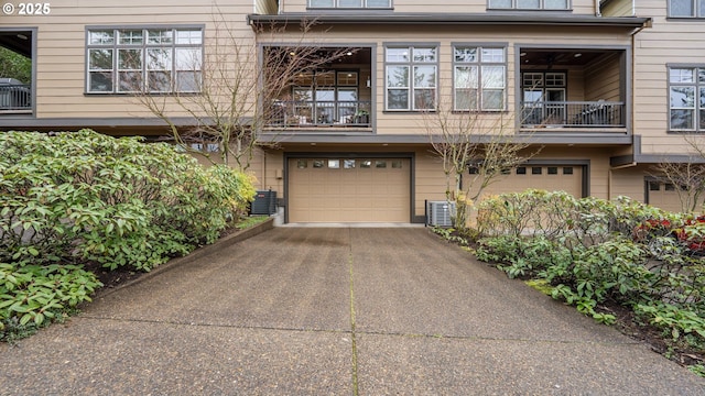 view of front of home with a garage, central air condition unit, a balcony, and aphalt driveway