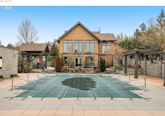 rear view of house featuring a pergola, a covered pool, and a patio