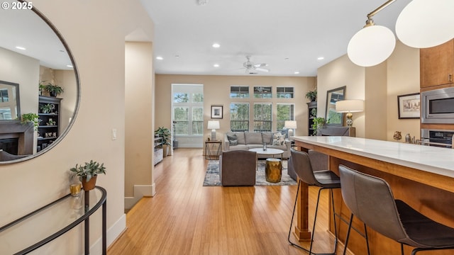 kitchen with light wood finished floors, stainless steel appliances, a ceiling fan, recessed lighting, and baseboards