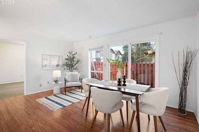 dining area with a textured ceiling, baseboards, and wood finished floors