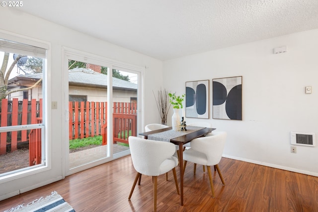 dining area featuring visible vents, baseboards, a textured ceiling, and wood finished floors