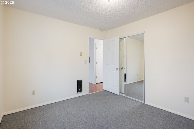 unfurnished bedroom with visible vents, baseboards, carpet floors, a closet, and a textured ceiling