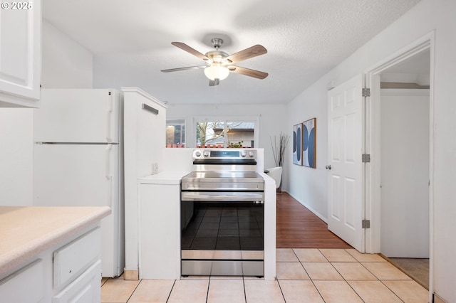 kitchen featuring white cabinetry, light tile patterned flooring, light countertops, and stainless steel range with electric cooktop