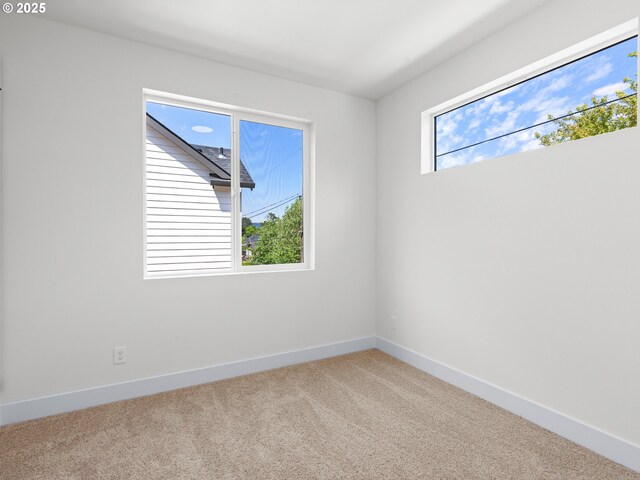 unfurnished room featuring baseboards and light carpet
