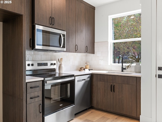 kitchen with light countertops, a sink, appliances with stainless steel finishes, and decorative backsplash