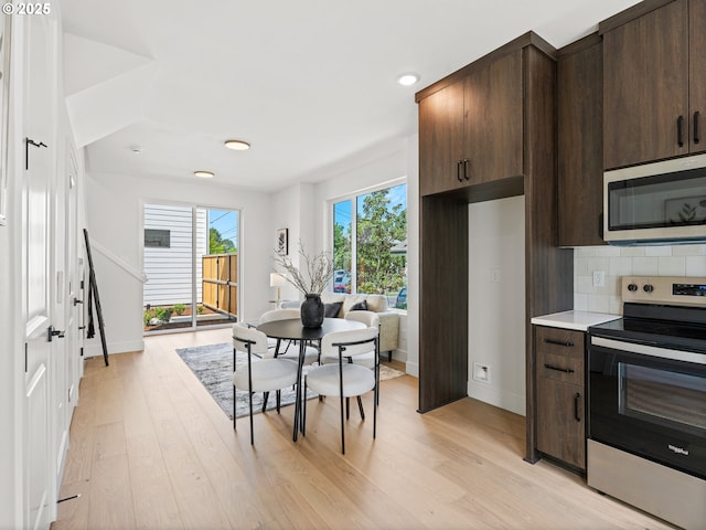 kitchen with stainless steel appliances, light wood-style flooring, decorative backsplash, and dark brown cabinetry