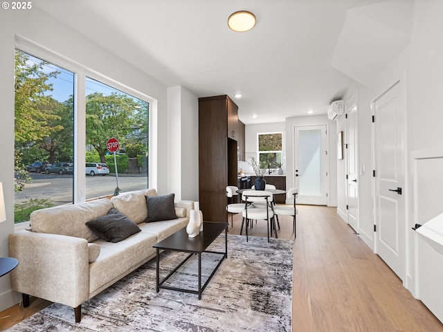 living room featuring light wood-style flooring, a wall mounted AC, and recessed lighting