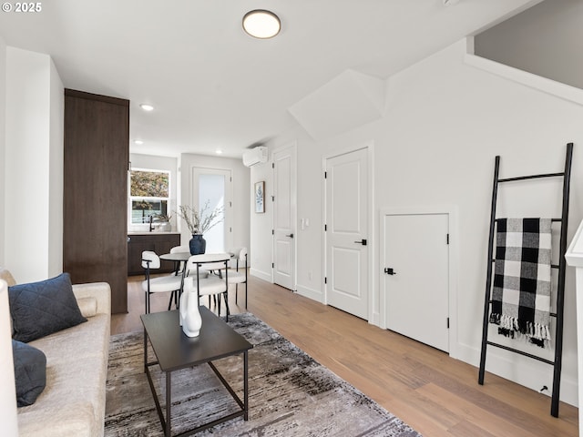 living room featuring baseboards, recessed lighting, a wall unit AC, and wood finished floors
