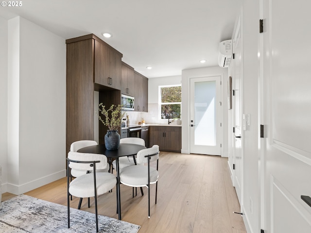 kitchen with a wall mounted air conditioner, recessed lighting, dark brown cabinetry, light wood finished floors, and appliances with stainless steel finishes