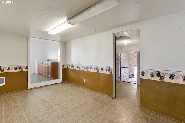 unfurnished room with wooden walls, light floors, wainscoting, and a textured ceiling