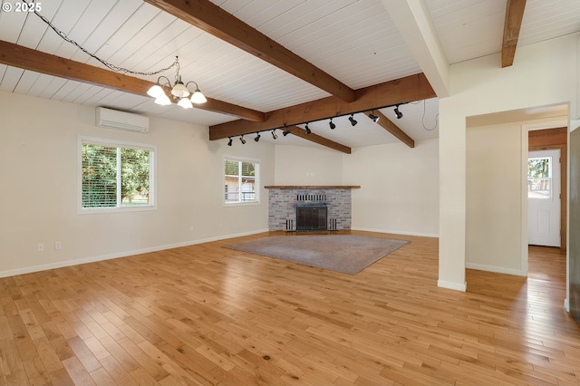 unfurnished living room featuring light wood finished floors, an inviting chandelier, a fireplace, and a wall unit AC