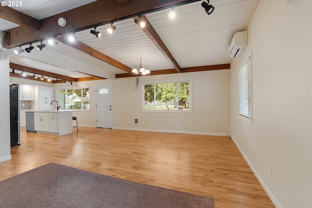 unfurnished living room featuring light wood-type flooring, a notable chandelier, and beamed ceiling