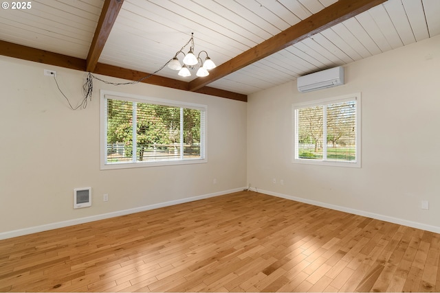 unfurnished room featuring an AC wall unit, baseboards, light wood-type flooring, and beam ceiling