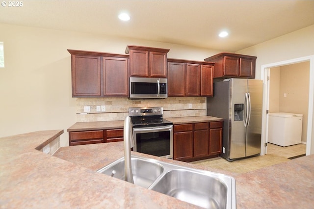 kitchen featuring appliances with stainless steel finishes, light countertops, decorative backsplash, recessed lighting, and a sink