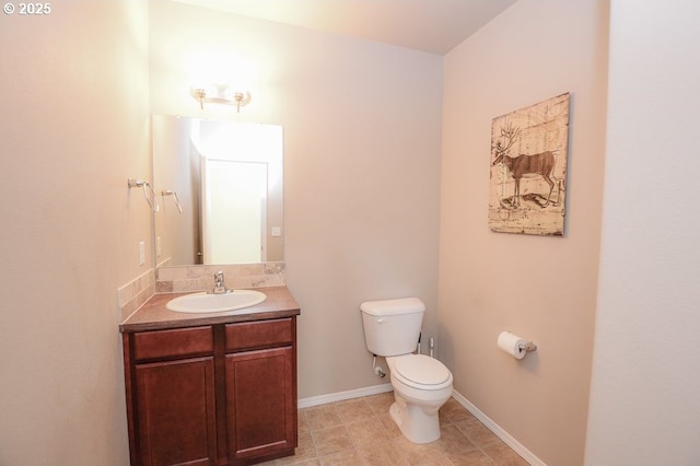 half bathroom with toilet, vanity, and baseboards
