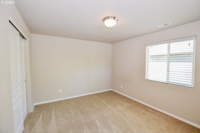 unfurnished bedroom with light carpet, a closet, and baseboards