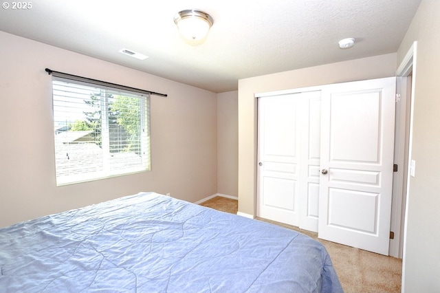 bedroom with light colored carpet, a closet, and baseboards