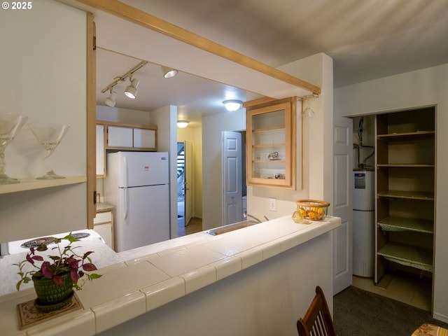 kitchen with refrigerator, water heater, freestanding refrigerator, a sink, and glass insert cabinets