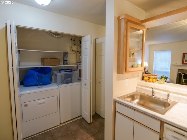 washroom featuring dark tile patterned floors, laundry area, washer and dryer, and a sink