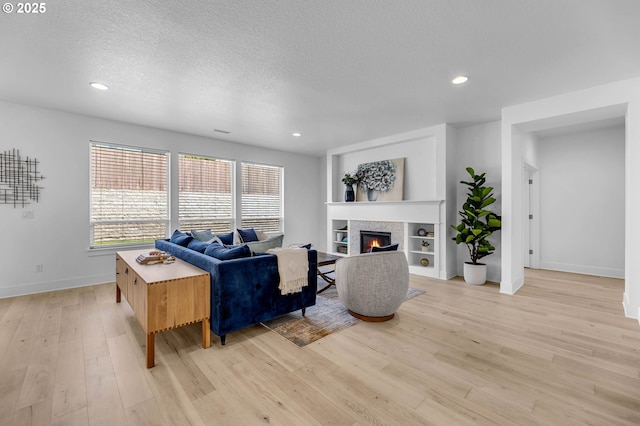 2928 S Harper Valley Way, Ridgefield, WA 98642 - living area with a glass covered fireplace, baseboards, recessed lighting, light wood-style flooring, and a textured ceiling