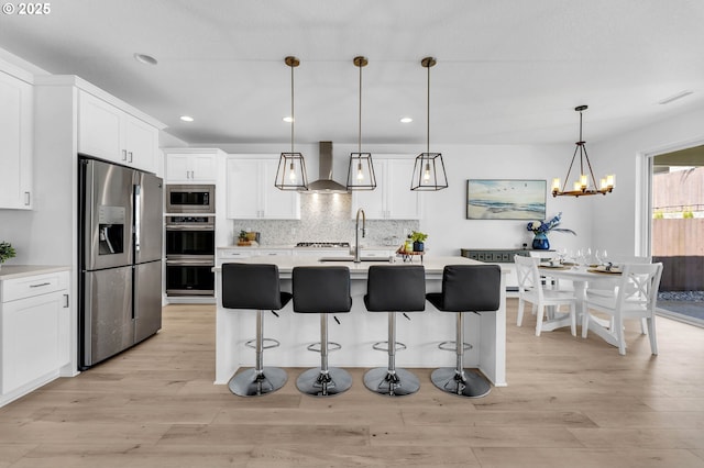 2928 S Harper Valley Way, Ridgefield, WA 98642 - kitchen with wall chimney range hood, light wood-type flooring, light countertops, and appliances with stainless steel finishes