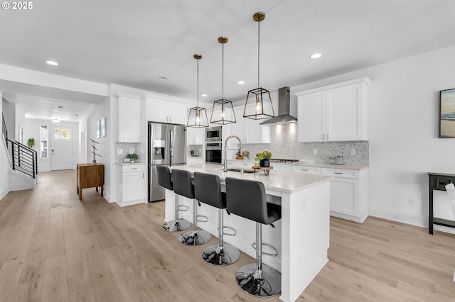 2928 S Harper Valley Way, Ridgefield, WA 98642 - kitchen with light countertops, wall chimney exhaust hood, decorative backsplash, stainless steel appliances, and light wood finished floors