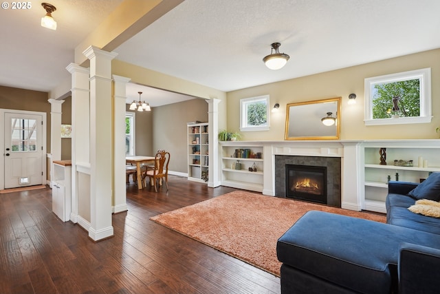 living room with ornate columns, a tile fireplace, dark wood-style floors, and baseboards