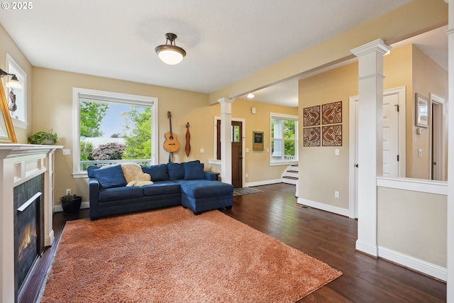 living room with ornate columns, dark wood finished floors, a fireplace, stairway, and baseboards