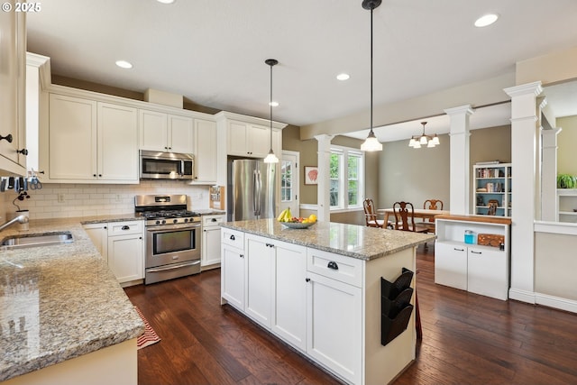 kitchen with appliances with stainless steel finishes, ornate columns, a sink, decorative backsplash, and dark wood-style floors