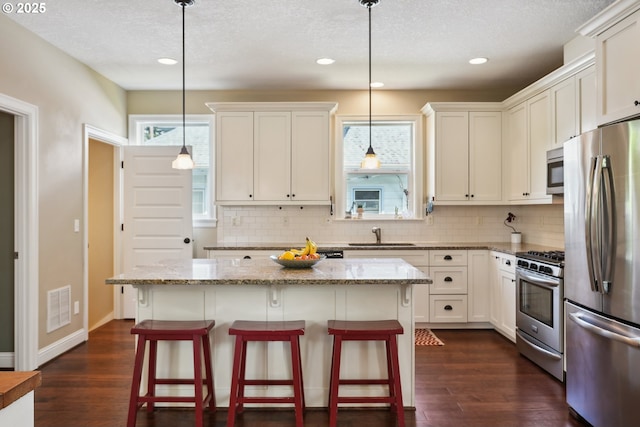 kitchen featuring stainless steel appliances, a sink, backsplash, recessed lighting, and light stone countertops