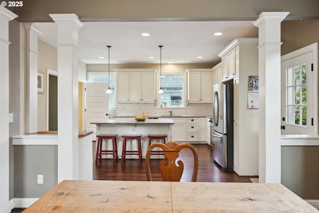 kitchen featuring freestanding refrigerator, ornate columns, dark wood-style floors, backsplash, and recessed lighting