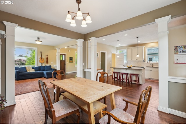 dining space featuring ornate columns, healthy amount of natural light, recessed lighting, and dark wood finished floors