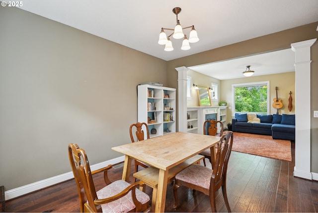 dining area featuring ornate columns, baseboards, dark wood finished floors, a fireplace, and a chandelier