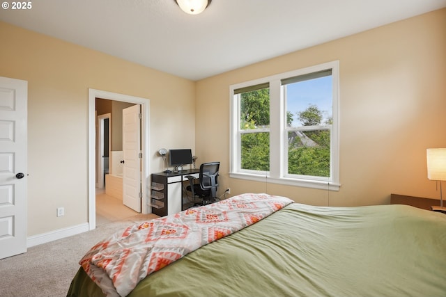 carpeted bedroom with baseboards, a desk, and ensuite bath