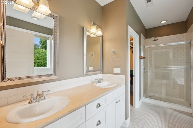 bathroom with a shower stall, double vanity, a spacious closet, and tile patterned floors