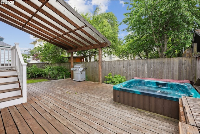 wooden terrace with an outdoor hot tub, a fenced backyard, and a grill
