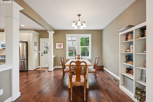 dining area featuring decorative columns, dark wood finished floors, baseboards, and a chandelier